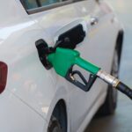 gas pump nozzle filling the white car